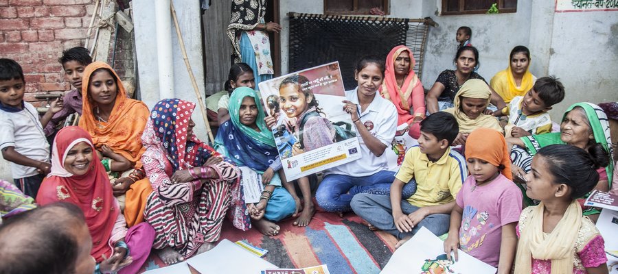 A health worker is showing an educational poster to a group of women and children