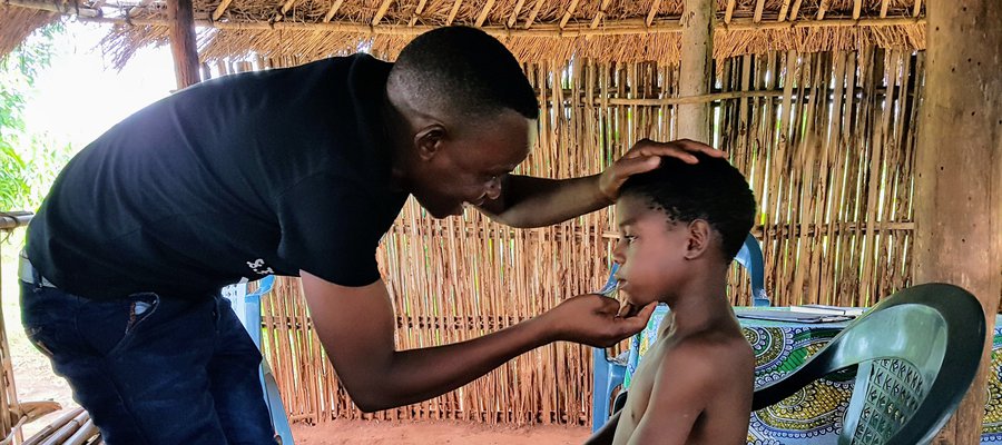 A Dr is examining a young boy's eyes