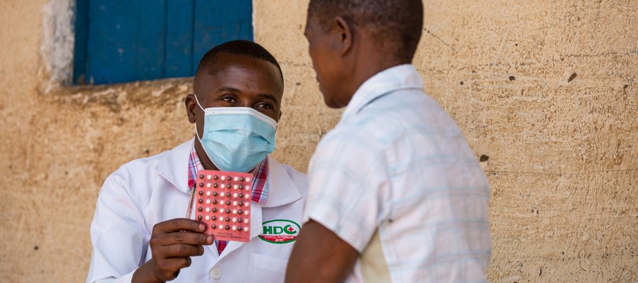 A health professional showing a blister pack of red and white tablets to a man