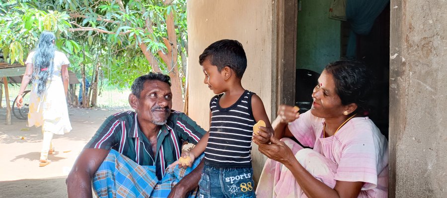 Mother, father and young son sitting outside at the door to their home